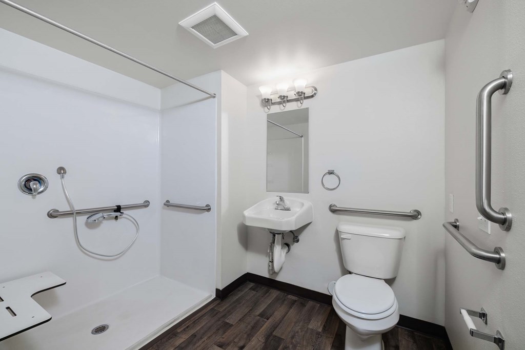 A white bathroom with a toilet, sink, and shower.