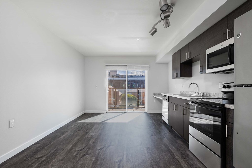 A modern kitchen with dark wood floors and stainless steel appliances.