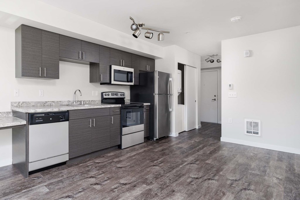 A kitchen with a black counter top and stainless steel appliances.