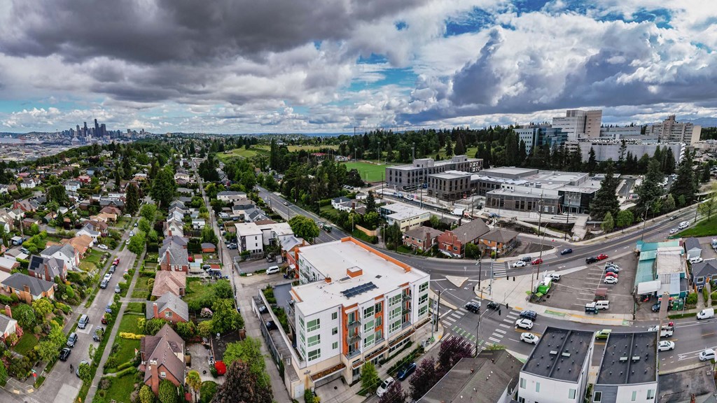 A cityscape with a mix of residential and commercial buildings, with a cloudy sky overhead.