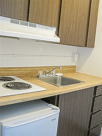 A kitchen with a stove top oven and a sink.