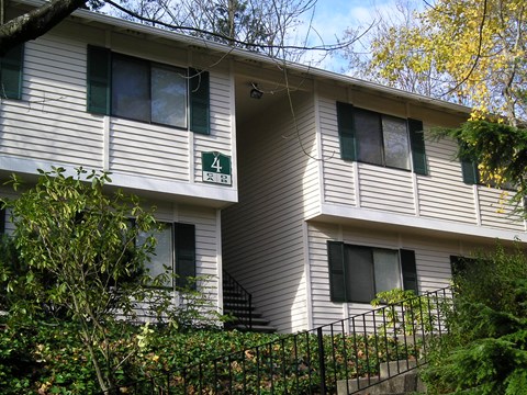 A white building with green shutters and a sign on the front.