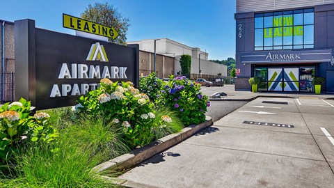 A sign for Airmark Apartments is displayed in front of a building with a leasing sign above it.