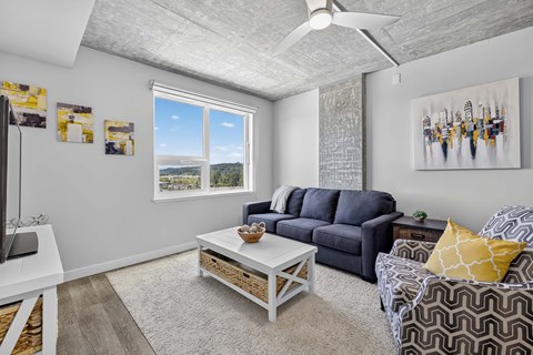 A living room with a grey sofa, a white coffee table, and a painting on the wall.