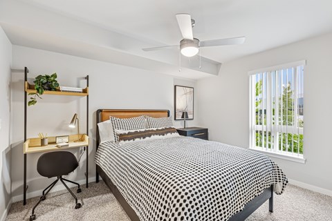 A bedroom with a bed, desk, and chair.