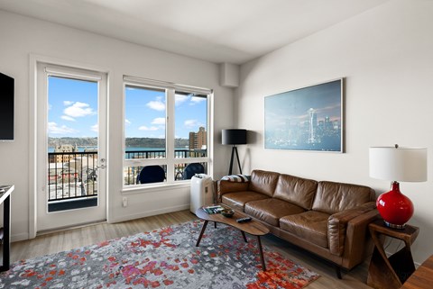 A living room with a brown leather couch, a red lamp, and a painting on the wall.