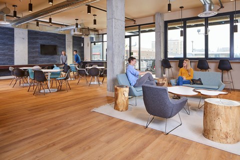 A modern office space with wooden floors and a mix of blue and grey furniture.