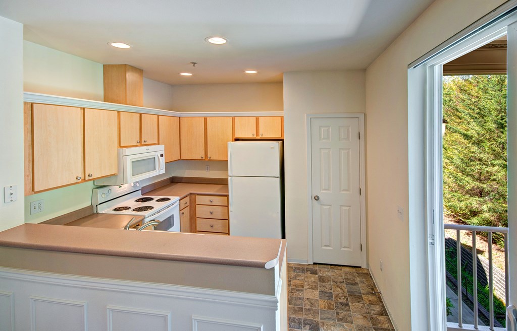 Kitchen with full appliances A kitchen with wooden cabinets and a tiled floor.