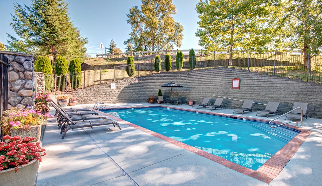 Outdoor pool A pool surrounded by a stone wall and trees.