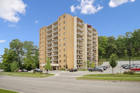 A tall apartment building with a parking lot in front.