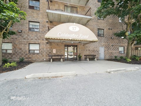 The entrance to a building named Coldwater Road is covered by a large umbrella.
