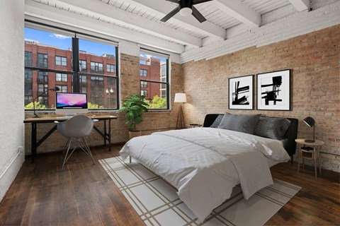 a bedroom with a bed and a brick wall and a desk with a computer