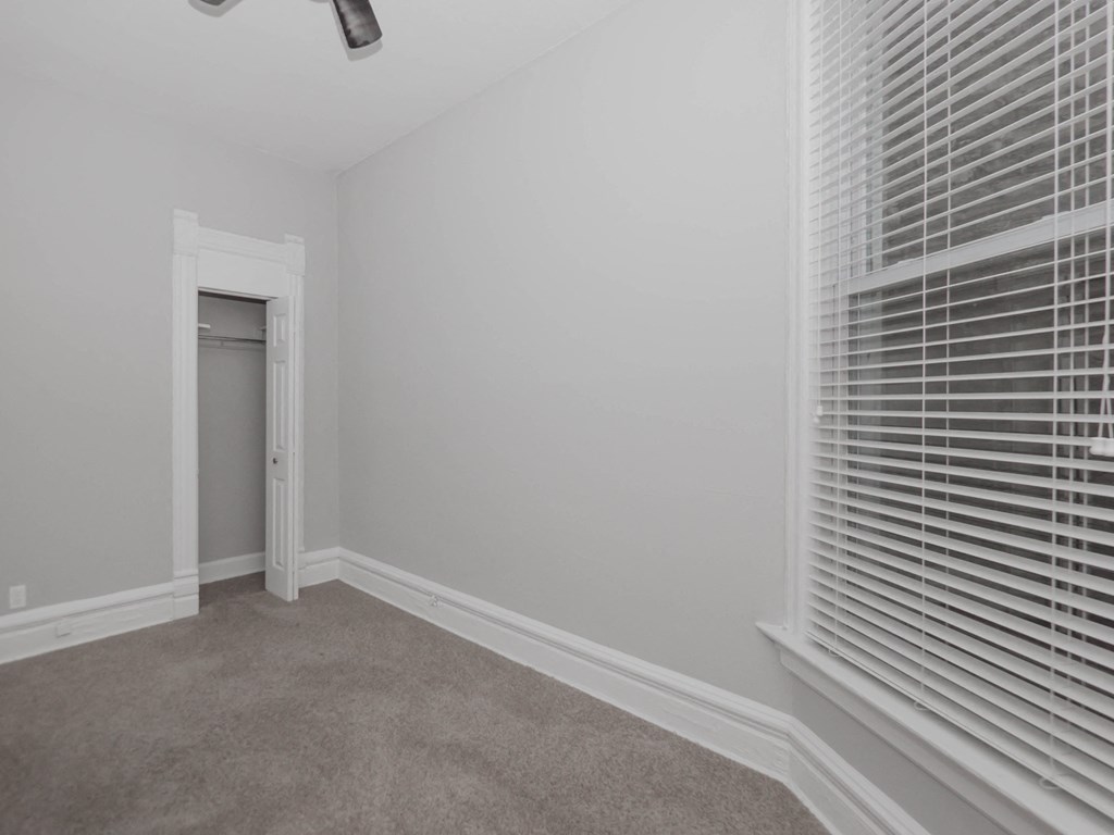 an empty room with white blinds and a door to a closet