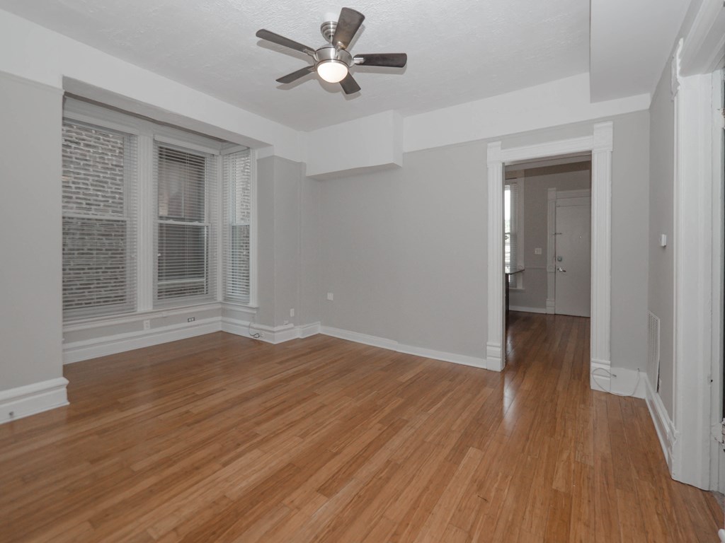 Apartment an empty living room with wood floors and a ceiling fan