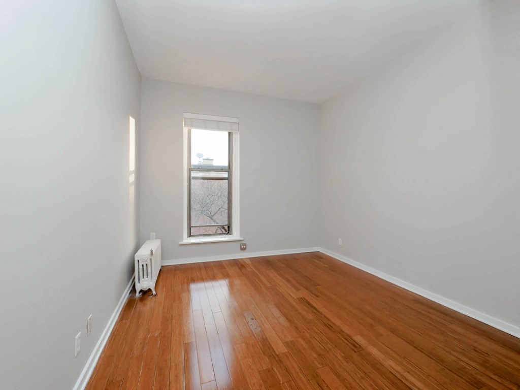 a room with white walls and a window and wooden floors