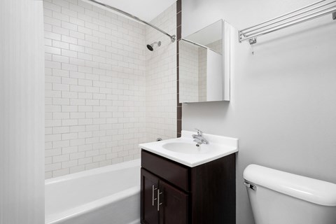 a bathroom with white tiles and a sink and a mirror