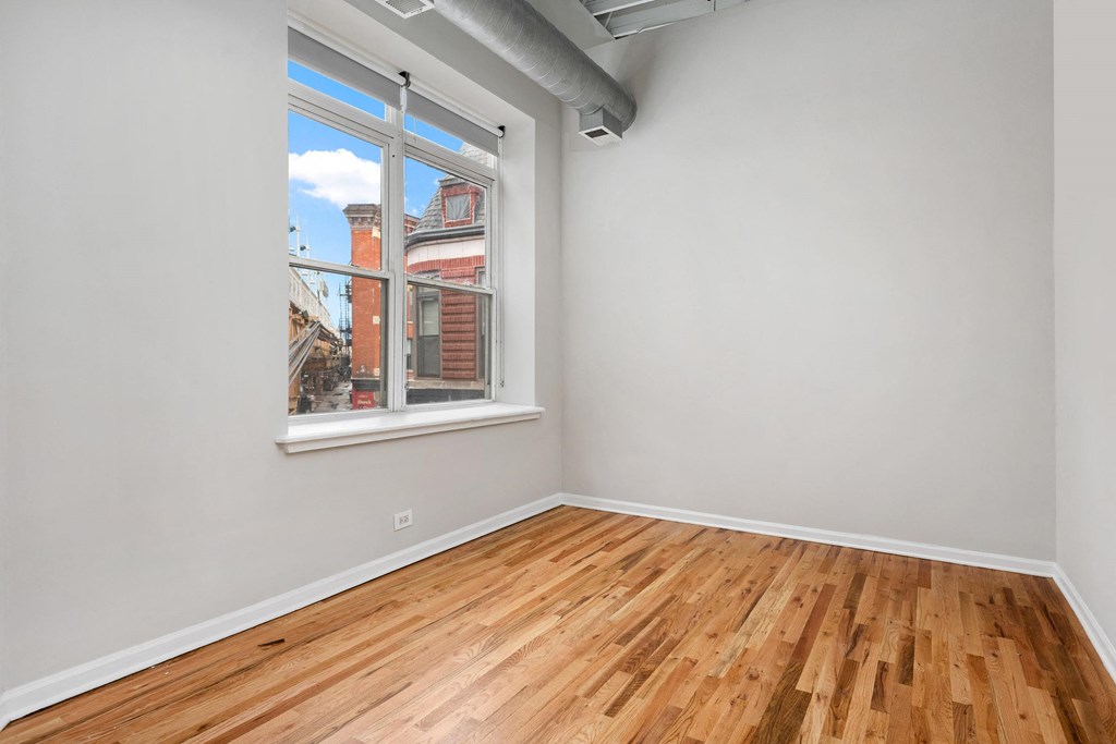 an empty room with wood floors and a large window
