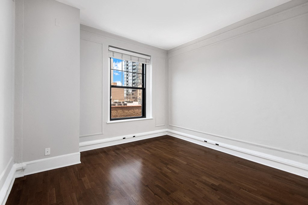 an empty bedroom with white walls and a window