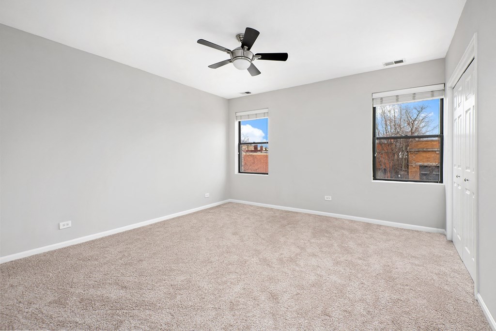 an empty living room with a ceiling fan and a window