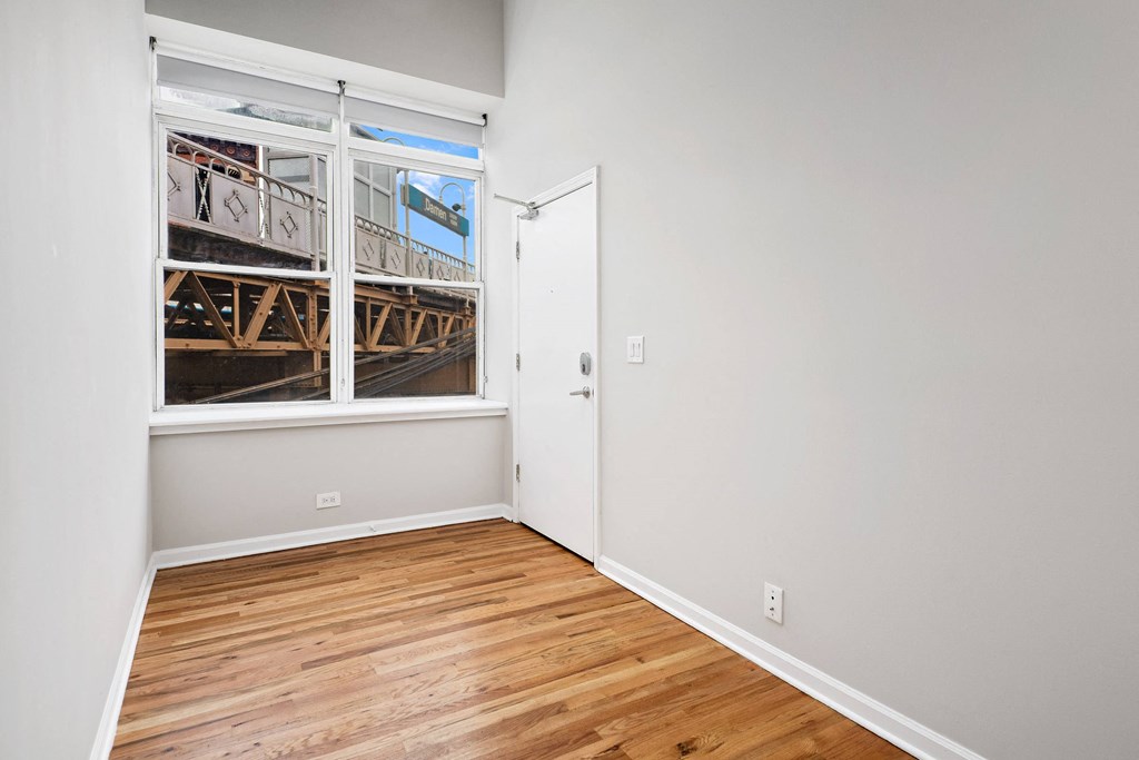 a room with white walls and a window and wood floors