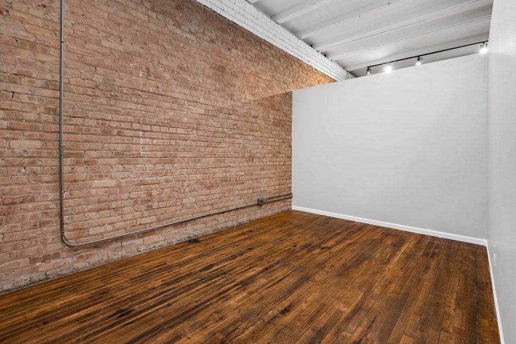an empty room with a brick wall and wood floors