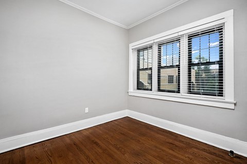 an empty bedroom with hardwood floors and a window