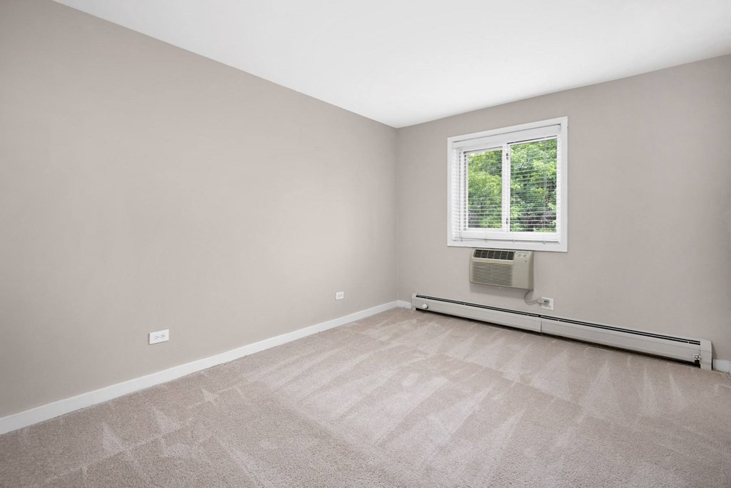 an empty room with a window and carpeting