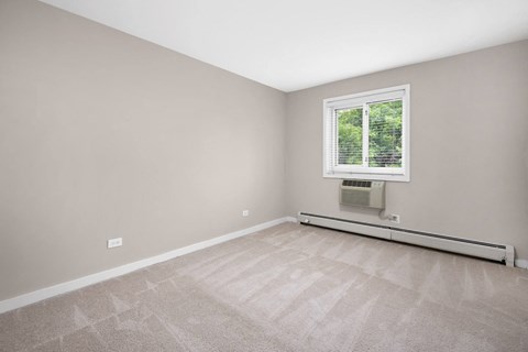 an empty room with a window and carpeting
