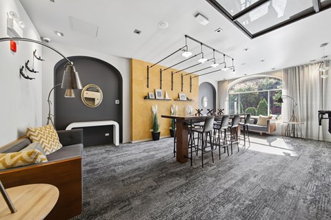 A modern living room with a grey carpet and a black sofa.