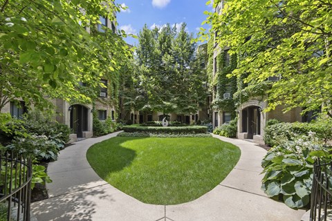 the courtyard of a building with a green lawn and trees