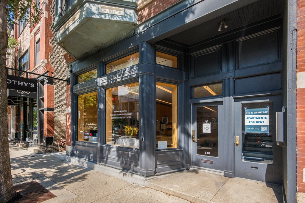 the front of a black building with windows and a sidewalk