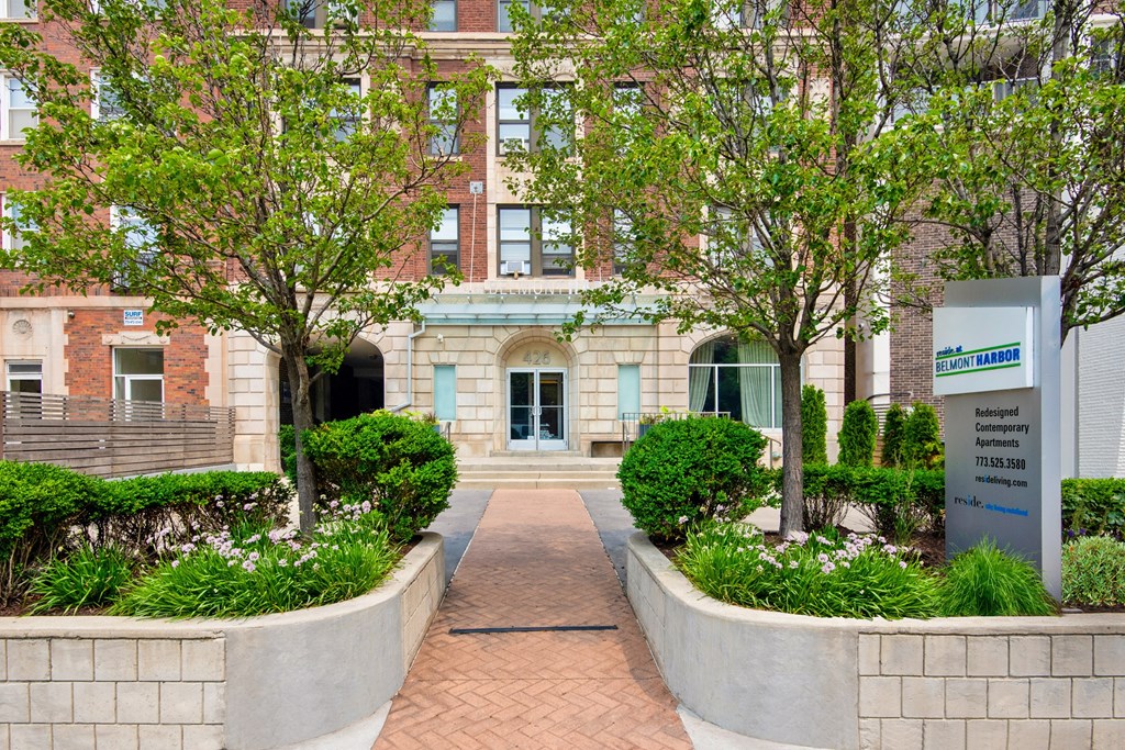 the front of a building with a walkway and trees
