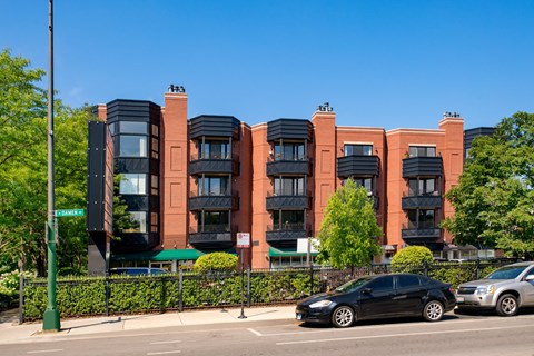 a row of apartment buildings on a city street with cars