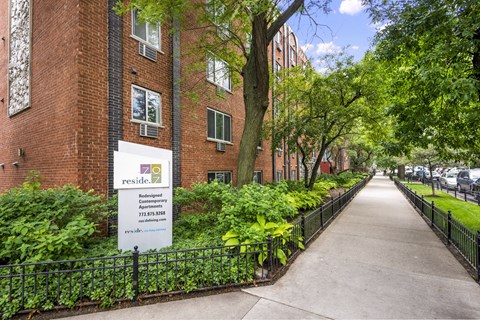 a sidewalk in front of a brick building with a sign