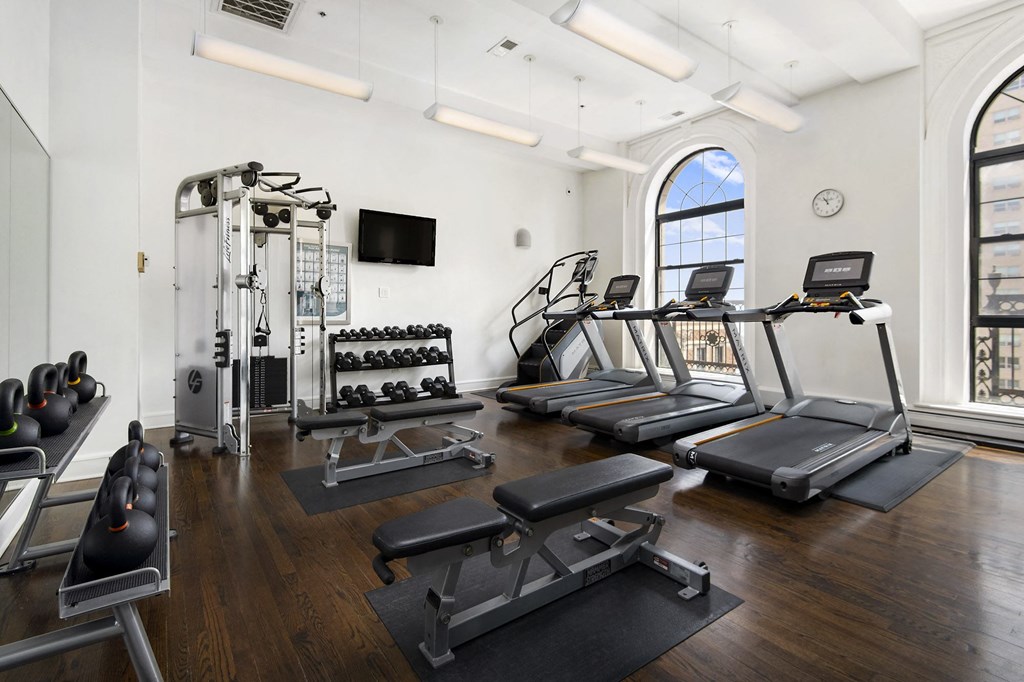 the gym with treadmills and weights in the corner of a room