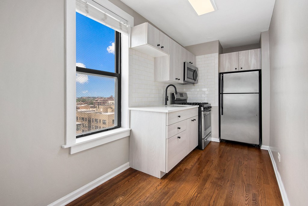 a kitchen with a large window and a stainless steel refrigerator
