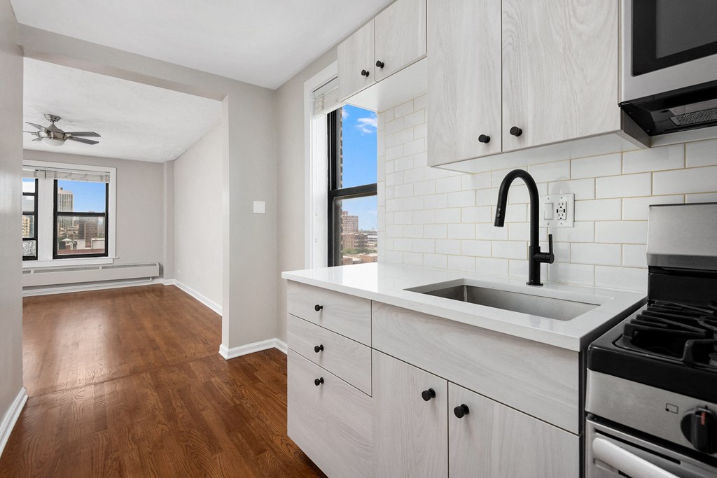 a kitchen with white cabinets and a sink and a window
