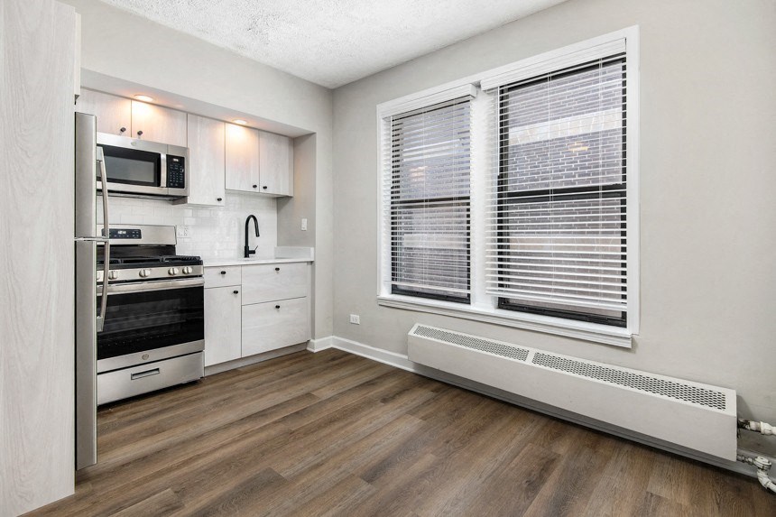Kitchen with hardwood floors, white cabinets and stainless steel appliances