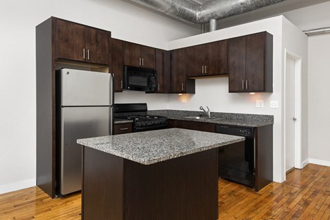 a kitchen with granite countertops and a stainless steel refrigerator