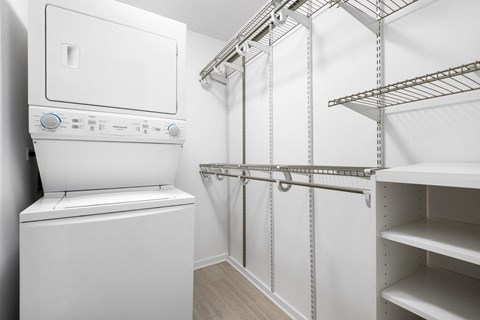 a laundry room with a washer and dryer and a closet with shelves