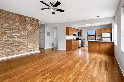 an empty living room with a brick wall and wood floors