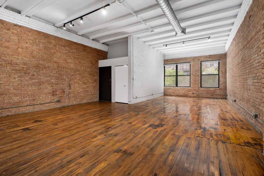 an empty room with wood floors and brick walls