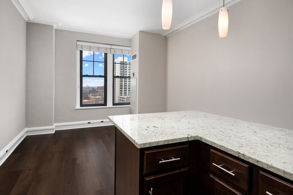 an empty kitchen with a marble counter top and a window