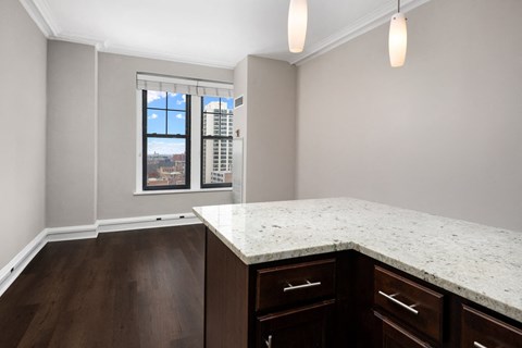an empty kitchen with a marble counter top and a window