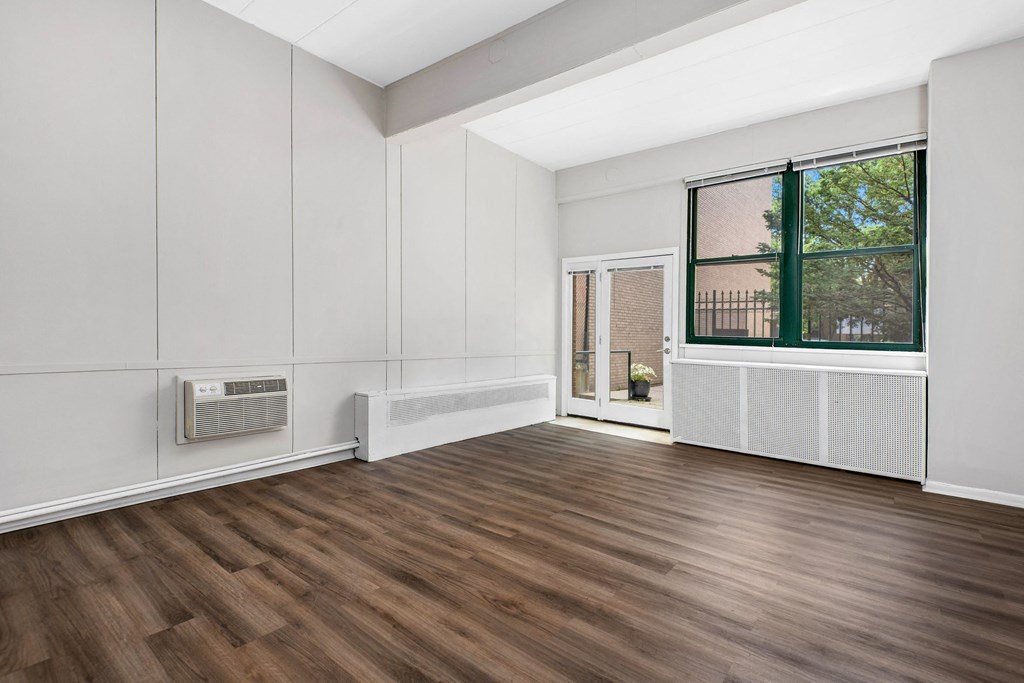 an empty living room with wood floors and a window