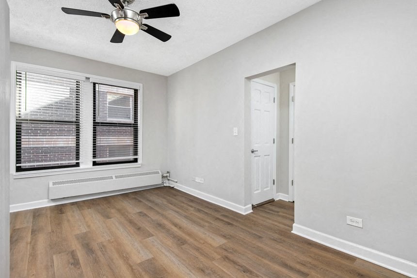 Living room with hardwood floors, white walls and a ceiling fan