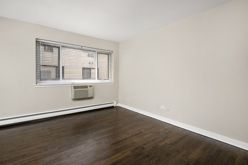 an empty living room with wood floors and a window