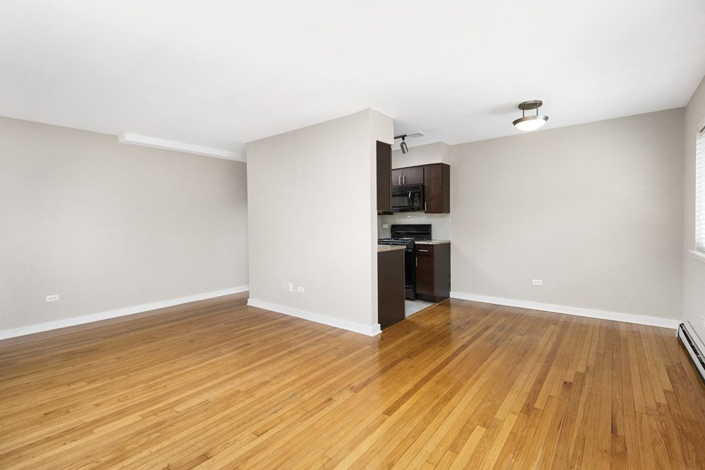 Apartment an empty living room with wood floors and a kitchen