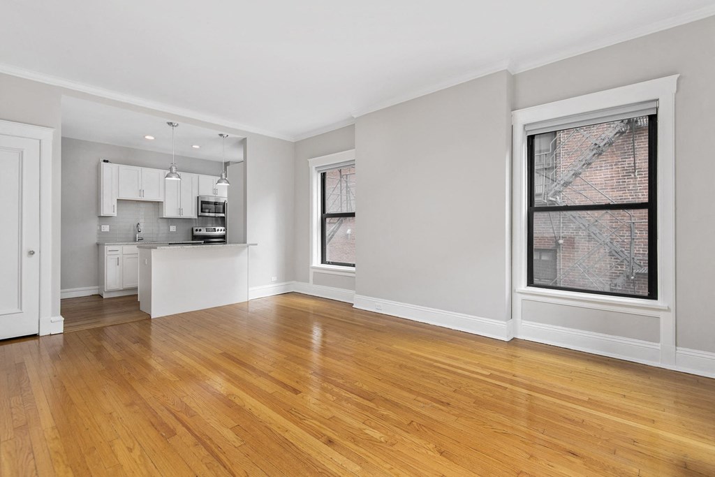 an empty living room with a kitchen and a large window