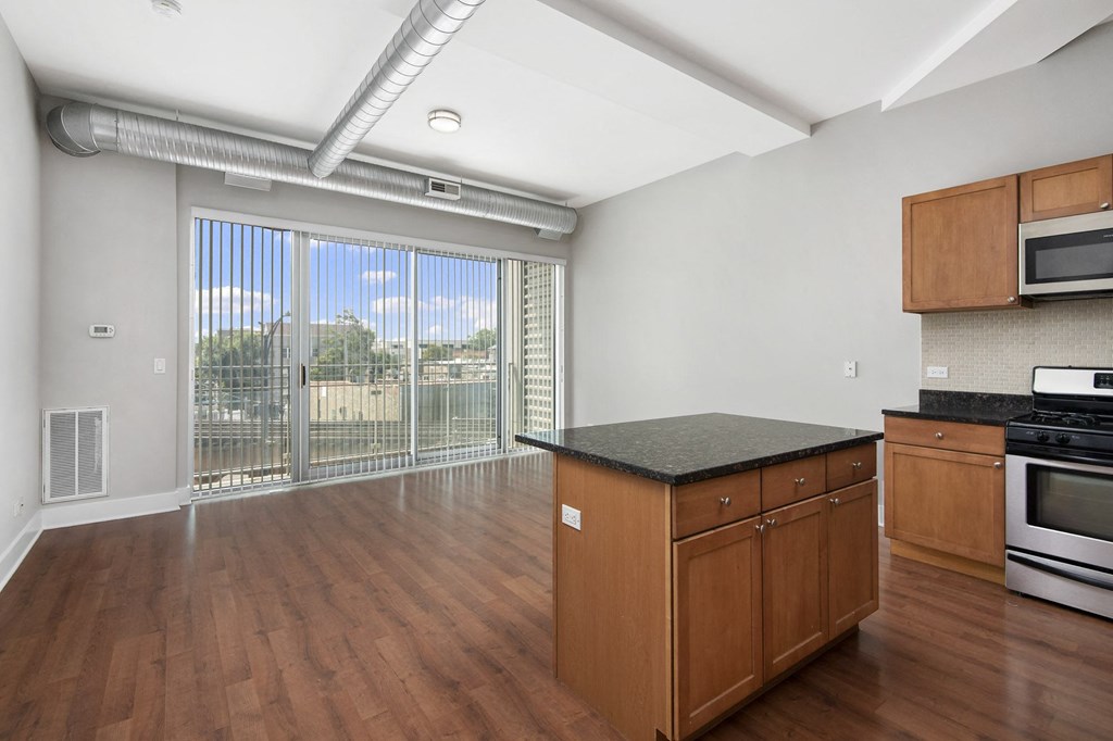 an empty kitchen with wood flooring and a large window